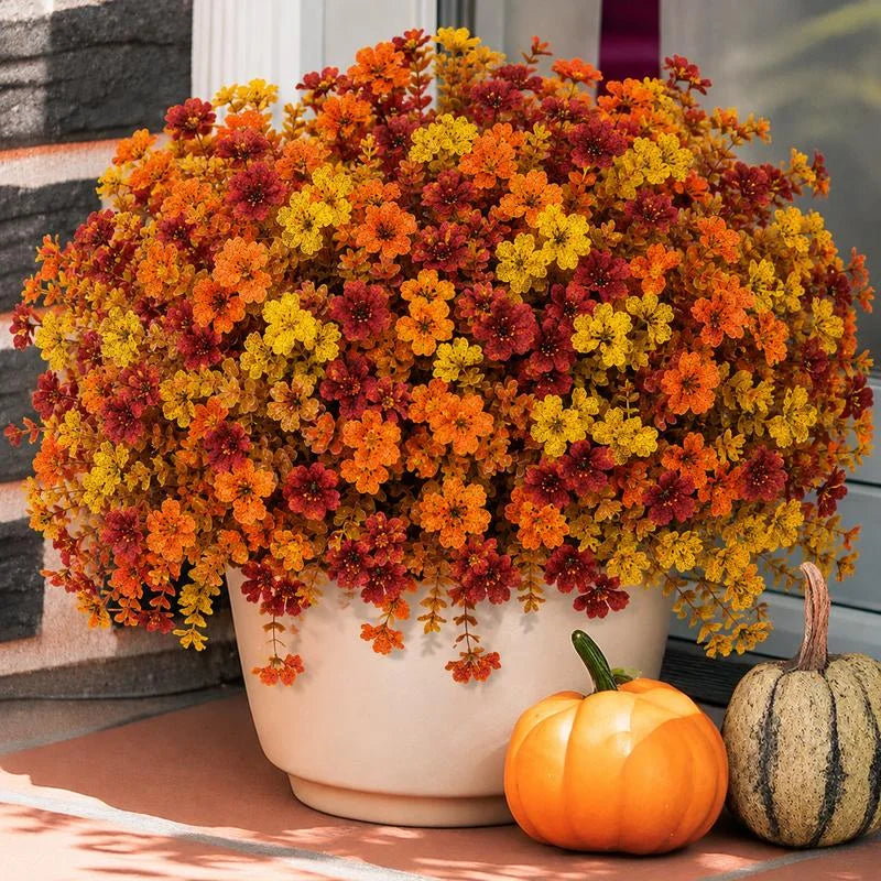 Artificial fall flowers styled in a cream planter; accessories not included